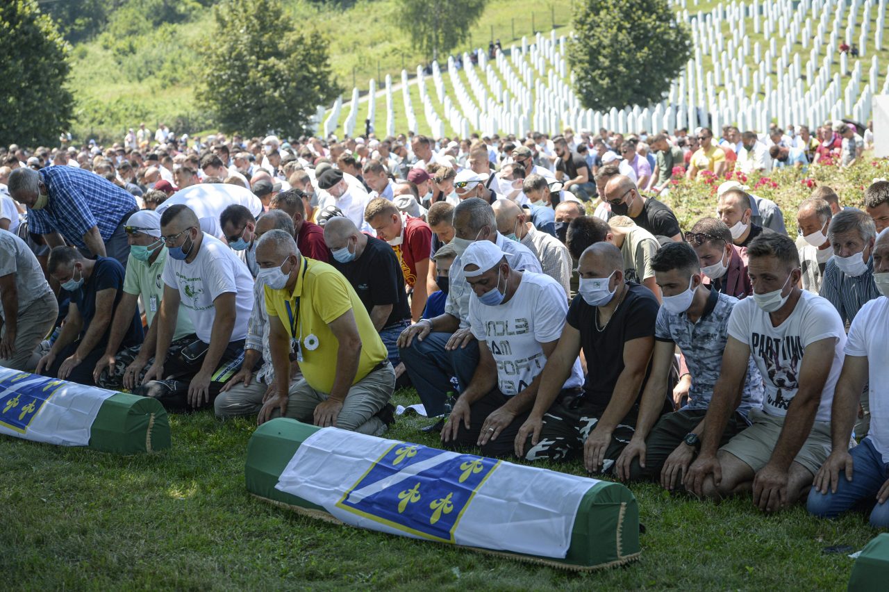 Bosnians pray by the coffins of nine massacre victims in Potocari, near Srebrenica, Bosnia, Saturday, July 11, 2020. Mourners converged on the eastern Bosnian town of Srebrenica for the 25th anniversary of the country's worst carnage during the 1992-95 war and the only crime in Europe since World War II that has been declared a genocide. (AP Photo/Kemal Softic)